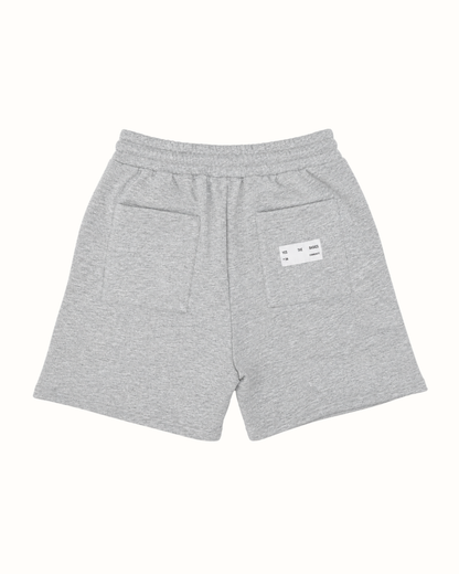 Light gray heathered sweat shorts with an elastic waistband, featuring a side pocket and a small white brand label on the back.