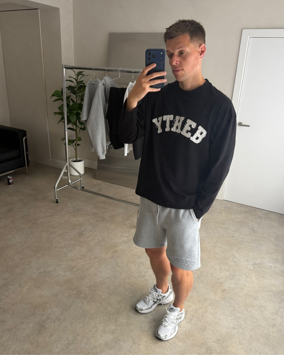 Man wearing the black YTHEB long sleeve oversized with grey marl shorts and white trainers