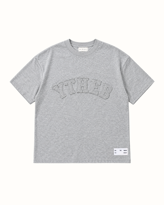 Grey marl T-shirt with arched YTHEB appliqué lettering in textured tonal grey, script signature neck label and woven hem label.